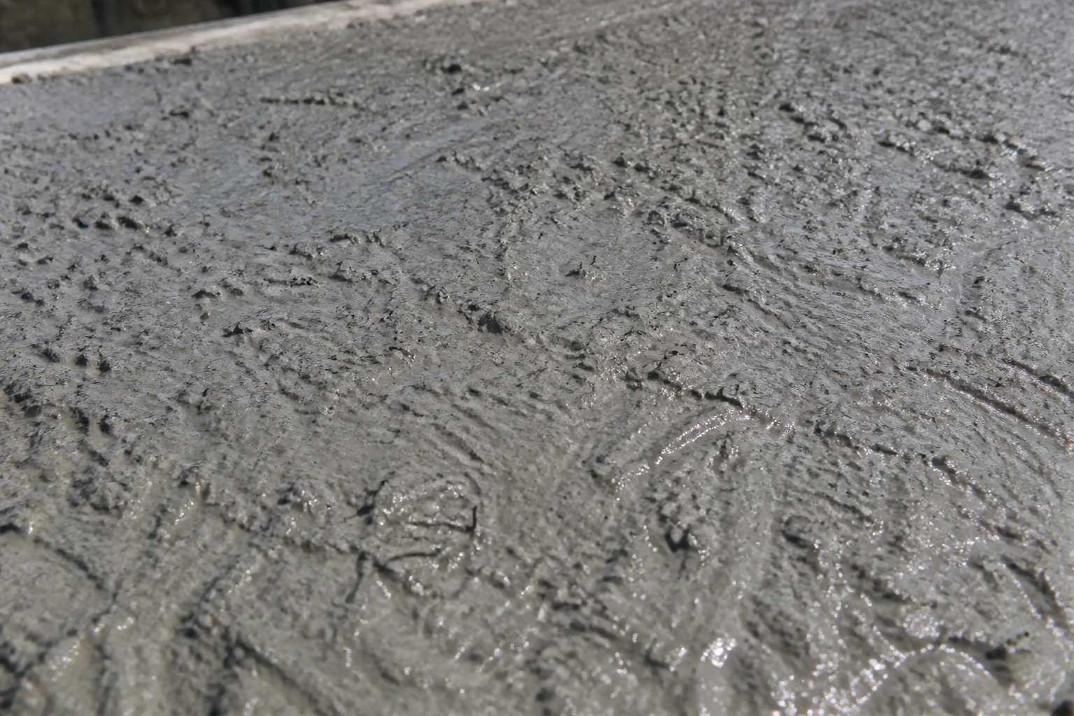 Surface de béton fibré fraîchement coulé avec fibres métalliques visibles dans la masse grise