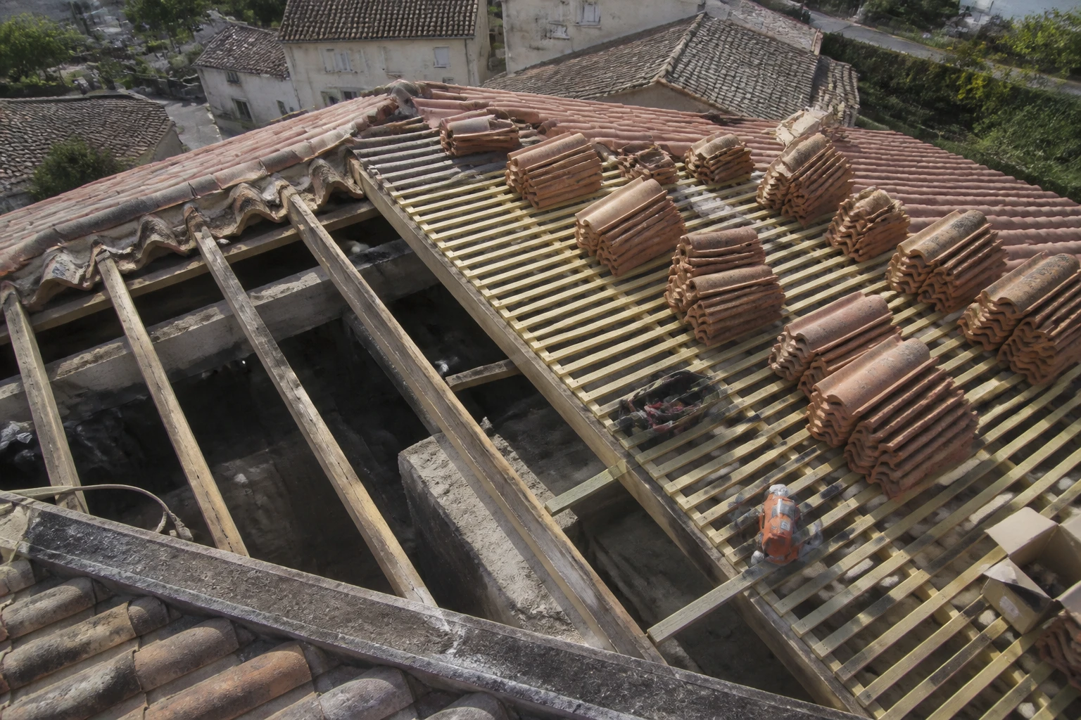 Vue plongeante d'un toit en réfection avec tuiles, chevrons et liteaux apparents